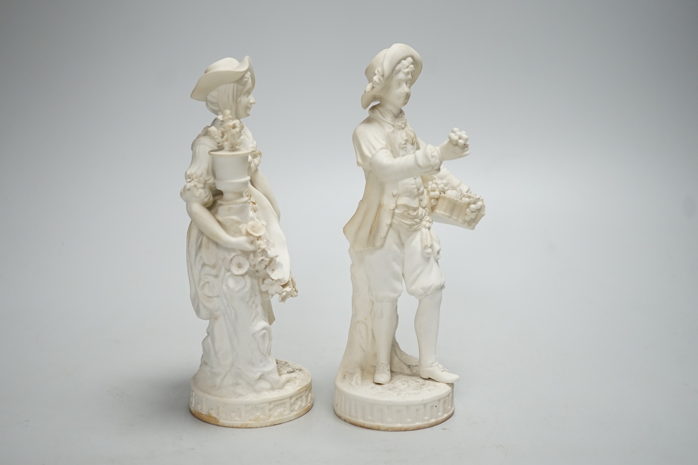 A pair of Minton biscuit figures of a boy and girl with flowers, on circular bases, 19cm